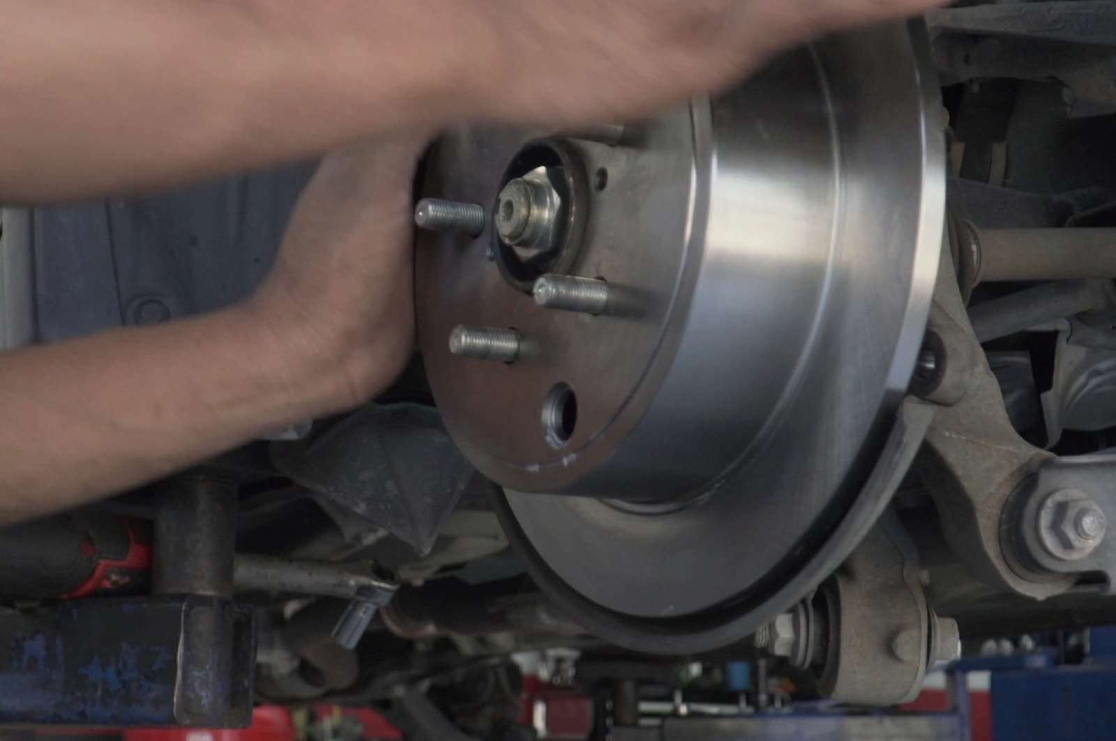 Bay Motors technician fitting a brake rotor on a lifted vehicle in Hayward